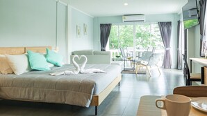 A hotel room with a bed, a dining area, and a TV. - The Beach Cha Am Suite (Cha-am)