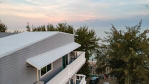 A modern building with a flat roof and large windows, overlooking a beach and ocean. - The Beach Cha Am Suite (Cha-am)