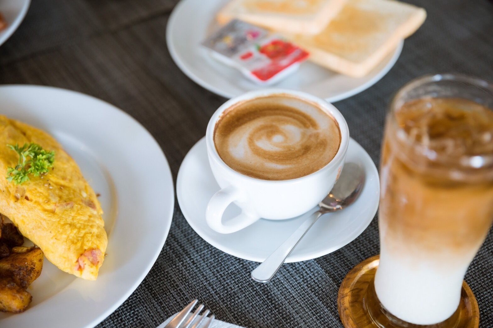 A breakfast setting with a cup of coffee, toast, and a glass of iced beverage on a table.