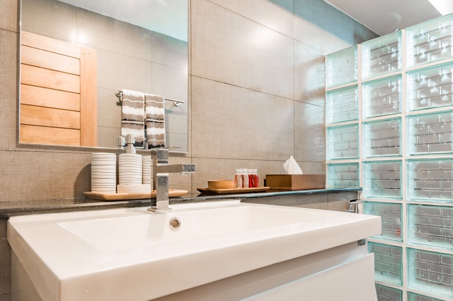 A modern bathroom with a large white sink, a mirror, and a towel rack.
