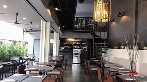A restaurant with a bar area, multiple tables and chairs, and a staircase leading to an upper level. - The Beach Cha Am Suite (Cha-am)