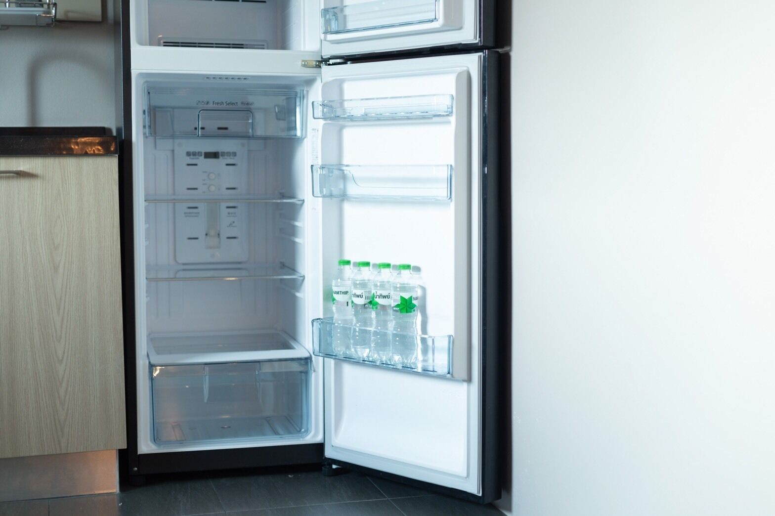 Un refrigerador abierto con botellas de agua en el estante de la puerta.