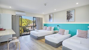 A hotel room with a balcony, two beds, a desk, and a chair.