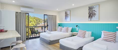 A hotel room with a balcony, two beds, a desk, and a chair.