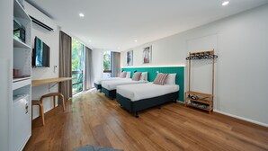 Una habitación de hotel moderna con dos camas, un escritorio y un armario.