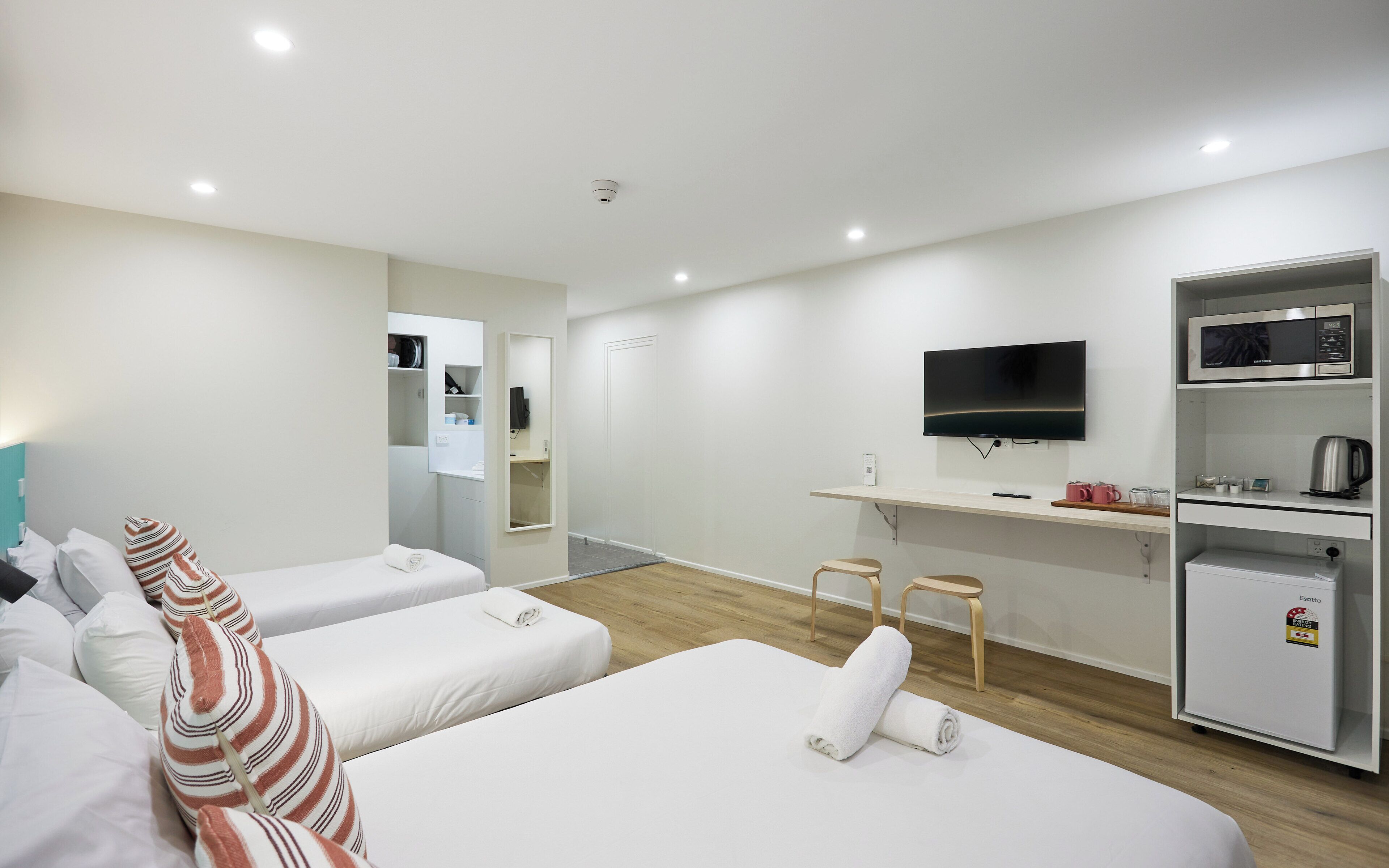 A hotel room with two beds, a TV, a microwave, a refrigerator, and a small seating area.