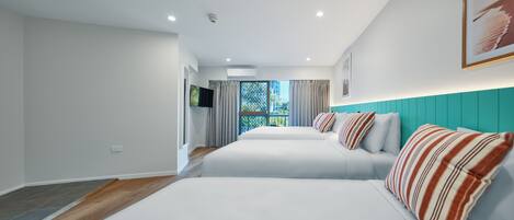 Un dormitorio moderno con dos camas, un ventanal grande y una pared de acento color aguamarina.