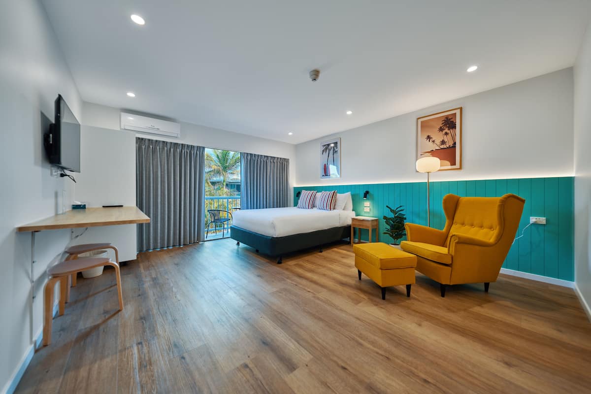 A modern hotel room with a bed, a desk, a chair, and a small table.
