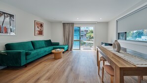 Una sala de estar moderna con un sofá verde, una mesa de centro de madera y una mesa de comedor de madera con sillas.