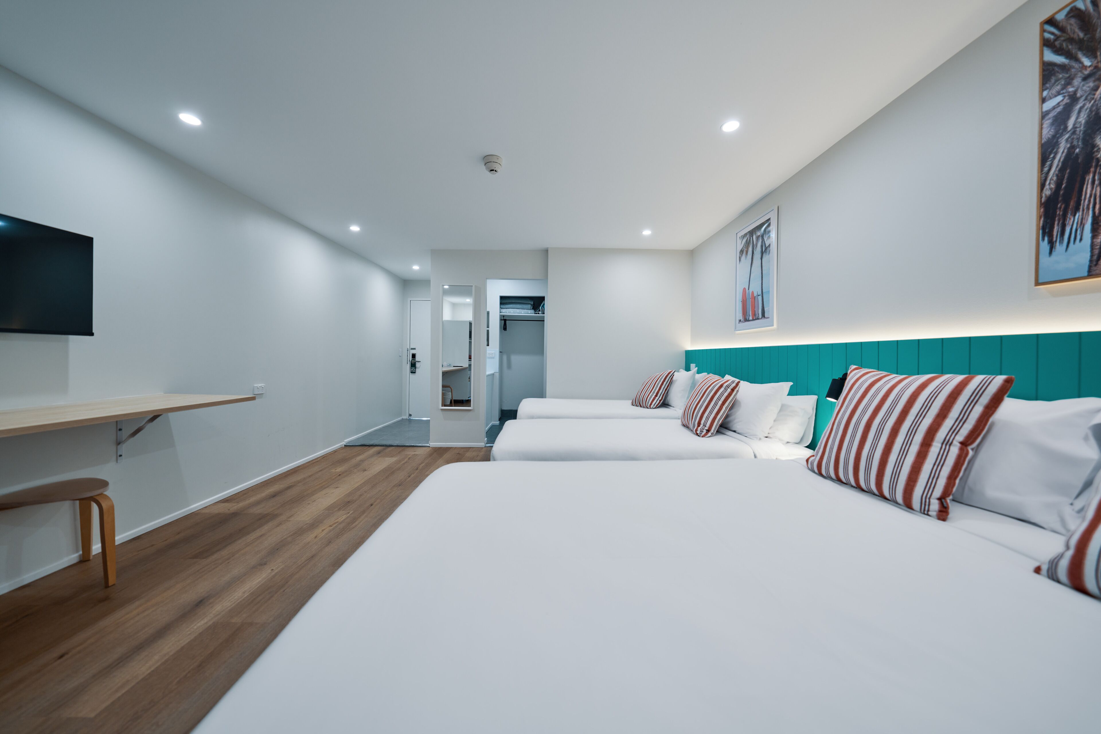 A hotel room with a long bed, a desk, and a television.
