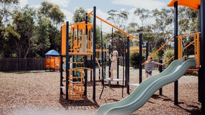 A playground with a slide, climbing structures, and a fenced area. - Scamander Sanctuary Holiday Park (Scamander)