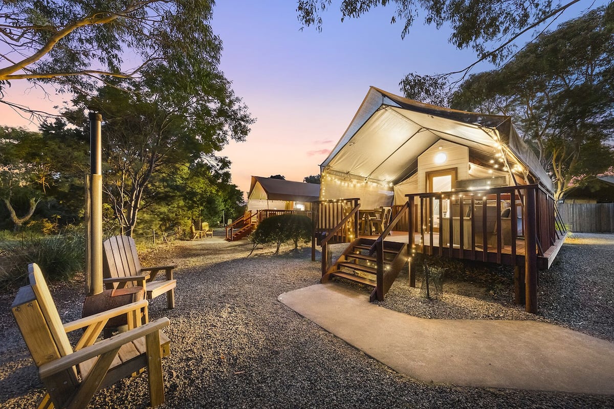 A cozy, tent-like structure with a wooden deck and stairs leading to a covered entrance.