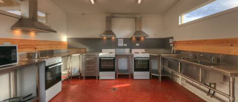 A modern kitchen with stainless steel appliances, wooden paneling, and a red floor.