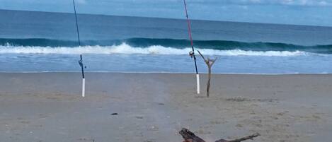 Een strand met een vuur en twee hengels.