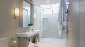 A modern bathroom with a glass shower enclosure, a sink with a mirror, and a towel rack.