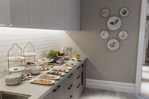 Enjoy a variety of dishes at our buffet, featuring multiple serving stations with fresh fruits, cheeses, and prepared foods.