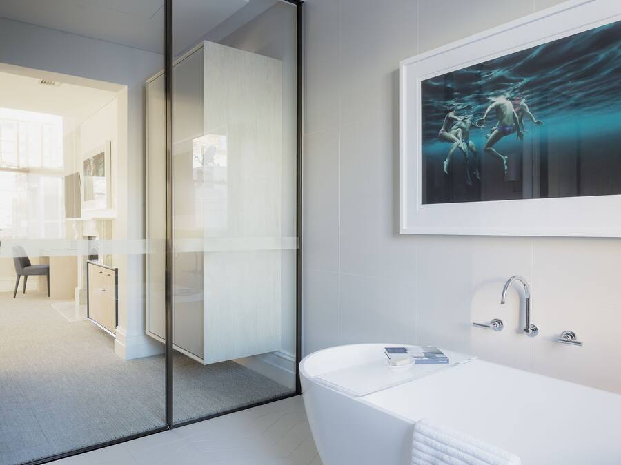 A modern bathroom with a freestanding bathtub, a glass shower enclosure, and a framed artwork above the sink.