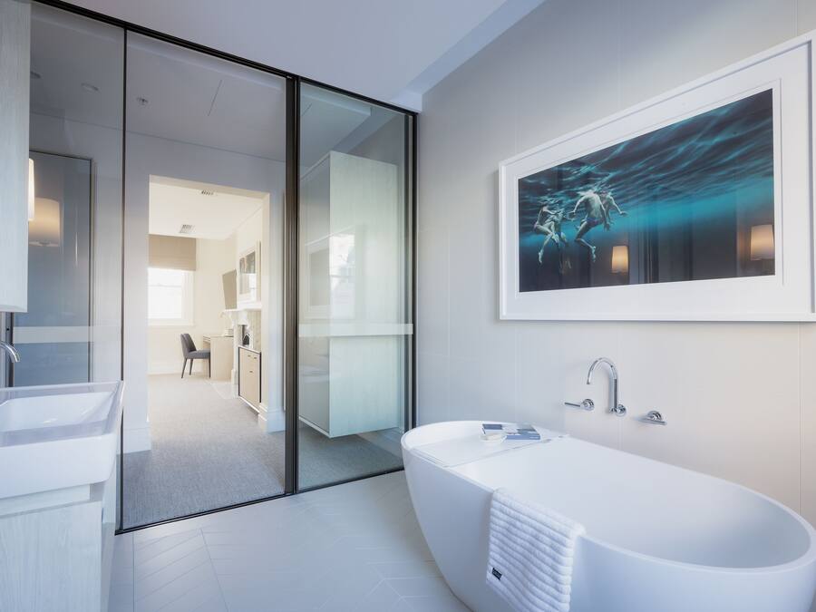 Un baño moderno con una bañera independiente, un cerramiento de ducha de vidrio y un espejo grande.