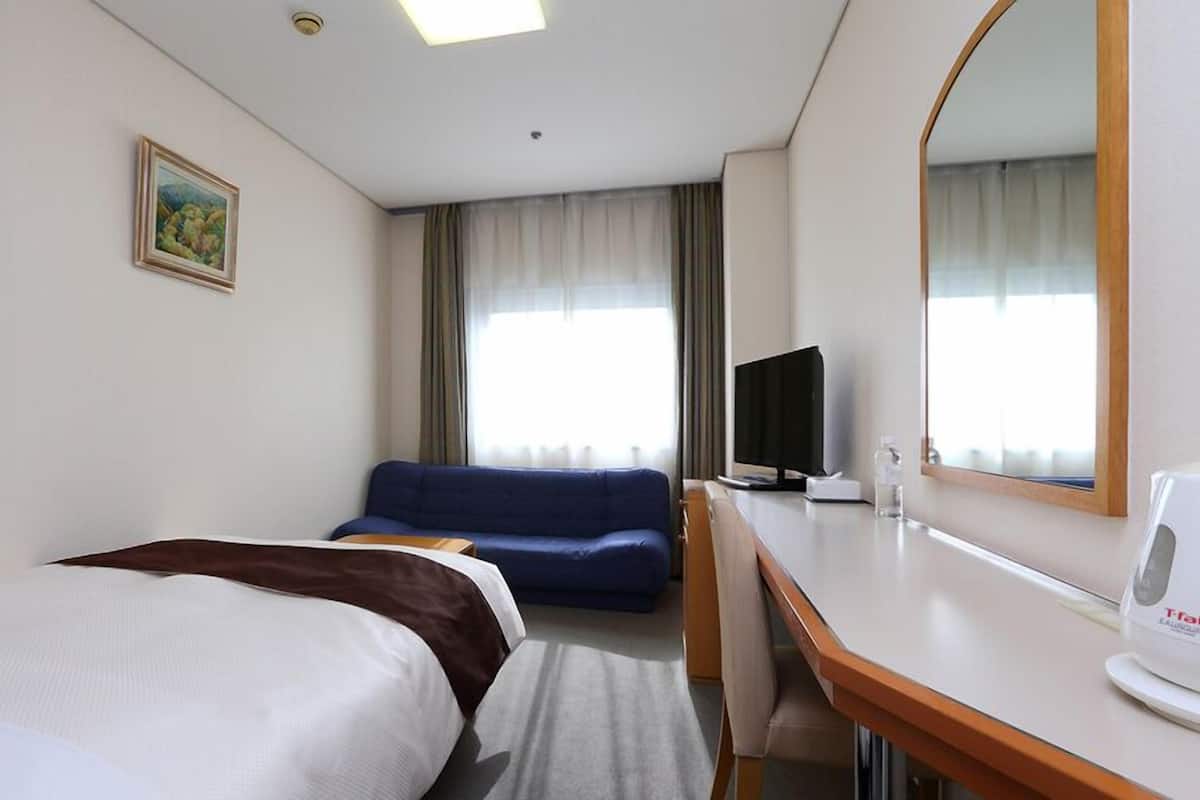 Une chambre d’hôtel avec deux lits, un bureau, une télévision et un grand miroir.