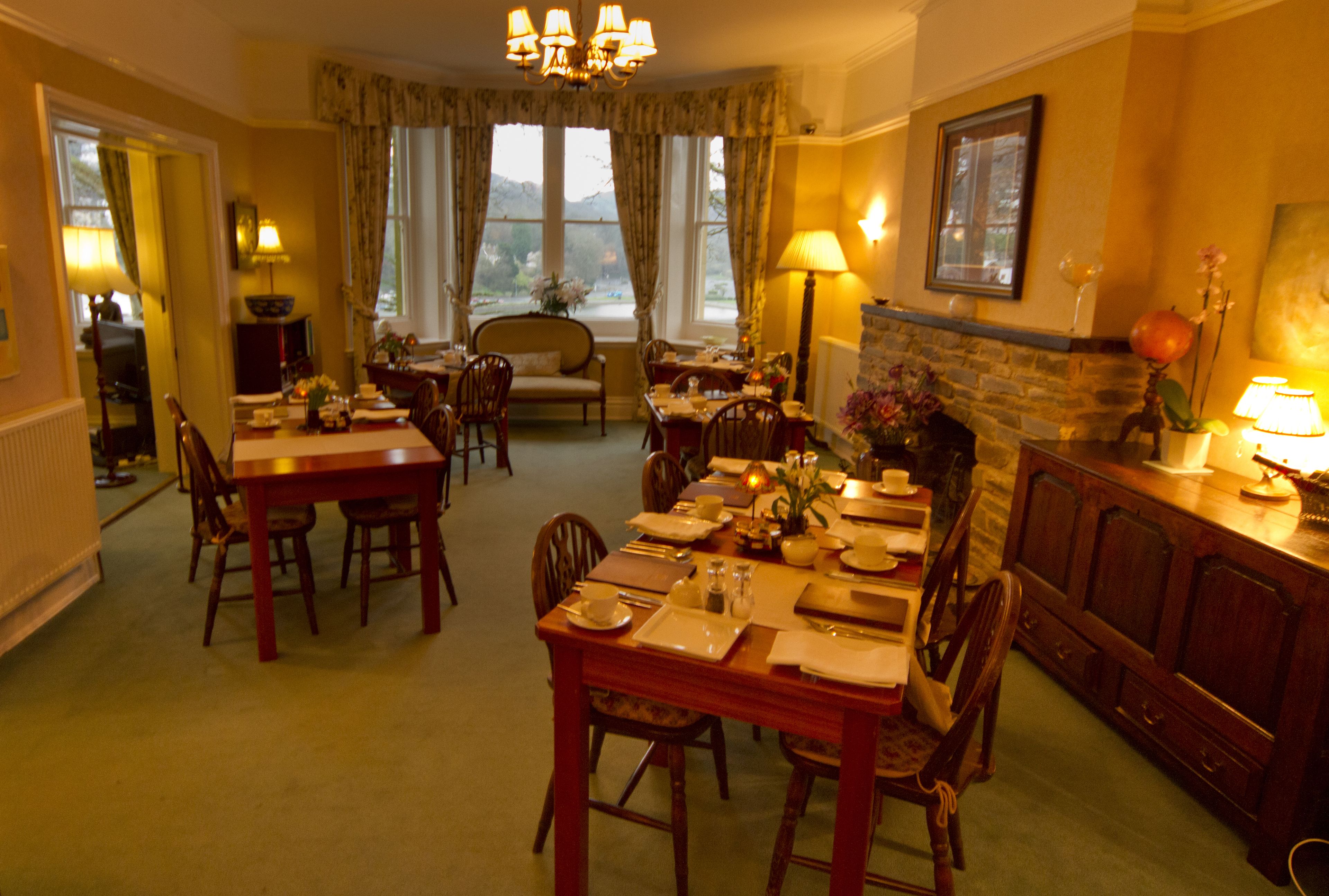 A dining area with a fireplace, dining table, chairs, and a view of the outdoors.