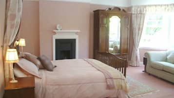A bedroom with a bed, a dresser, a mirror, a fireplace, and a window with curtains.