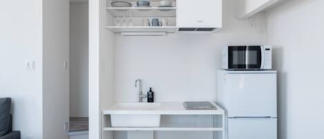 A modern kitchen with white cabinetry, a built-in microwave, and a sink.