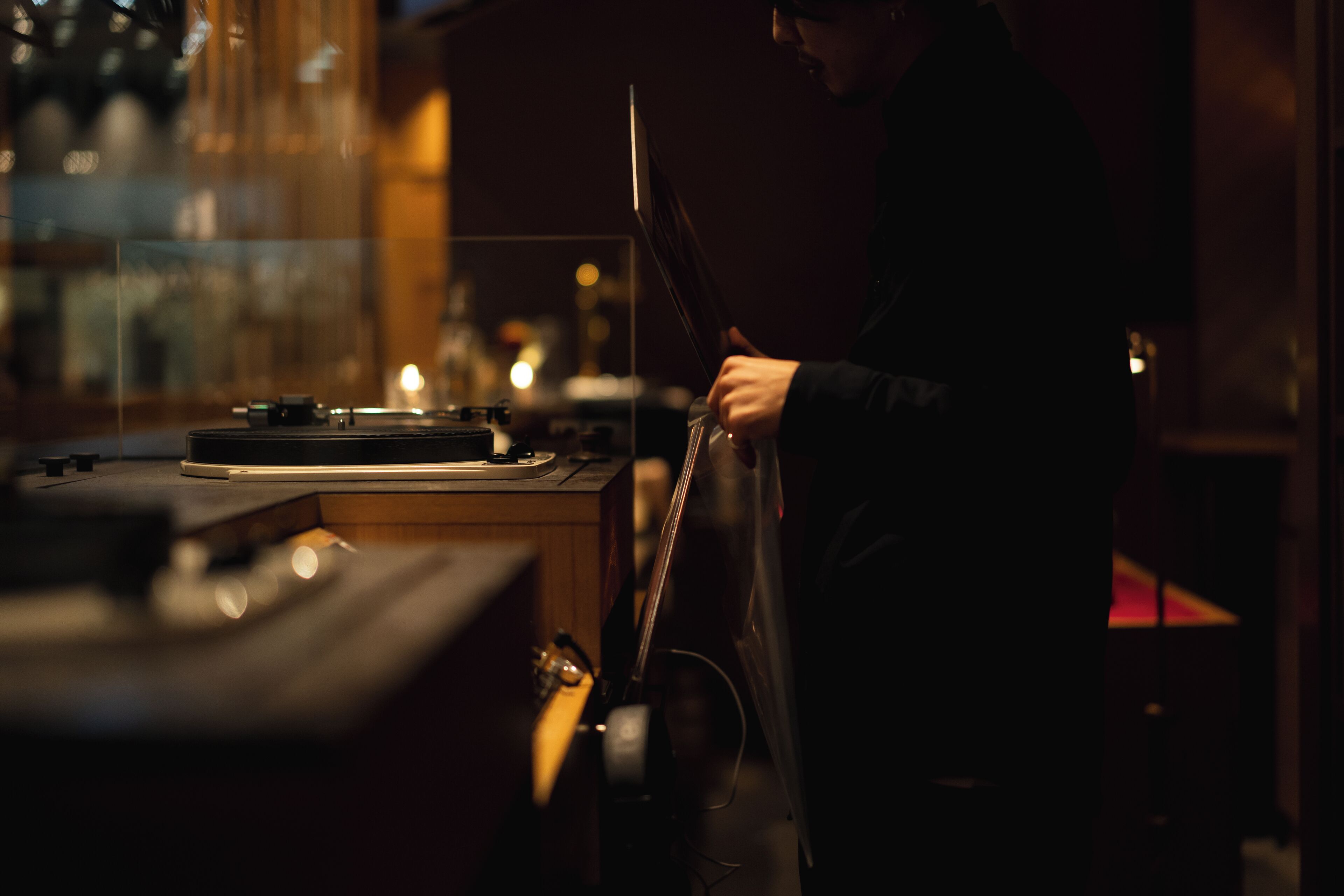 A person standing by a table with a turntable and a guitar.