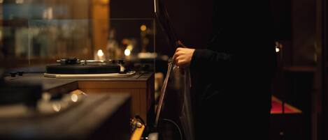 A person standing by a table with a turntable and a guitar.