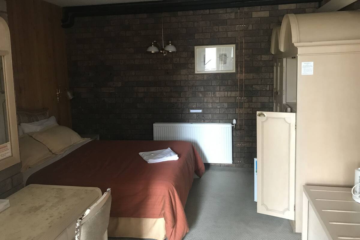 Een kamer met een bed, een radiator, een raam en een deur.