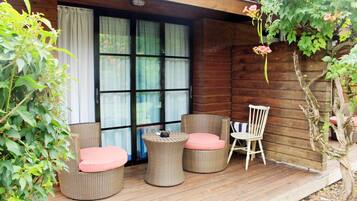A wooden deck with wicker furniture, including round chairs and a table.