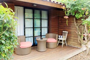 A wooden deck with wicker furniture, including round chairs and a table.