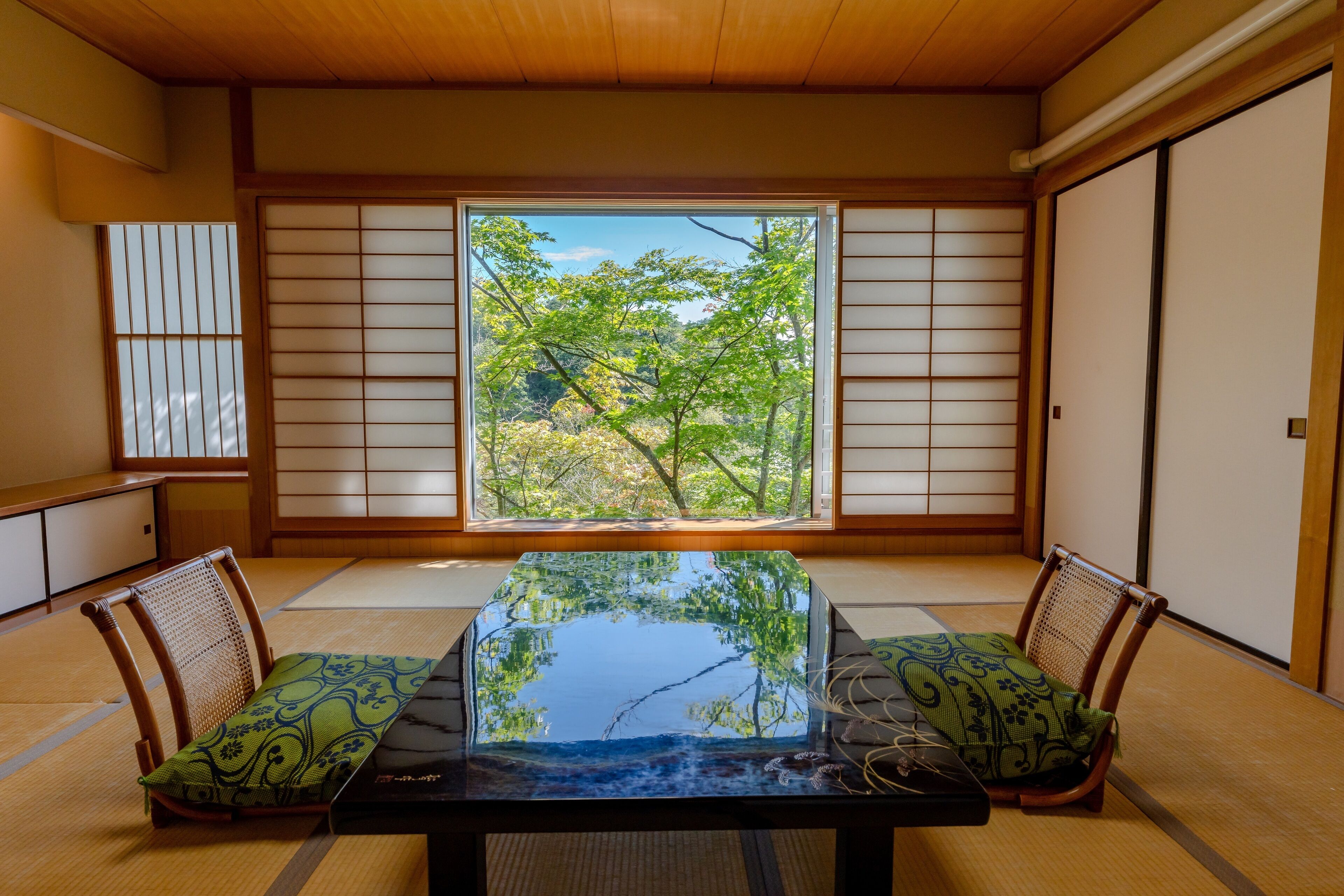 Una habitación japonesa tradicional con suelo de tatami, una mesa baja y puertas correderas shoji.