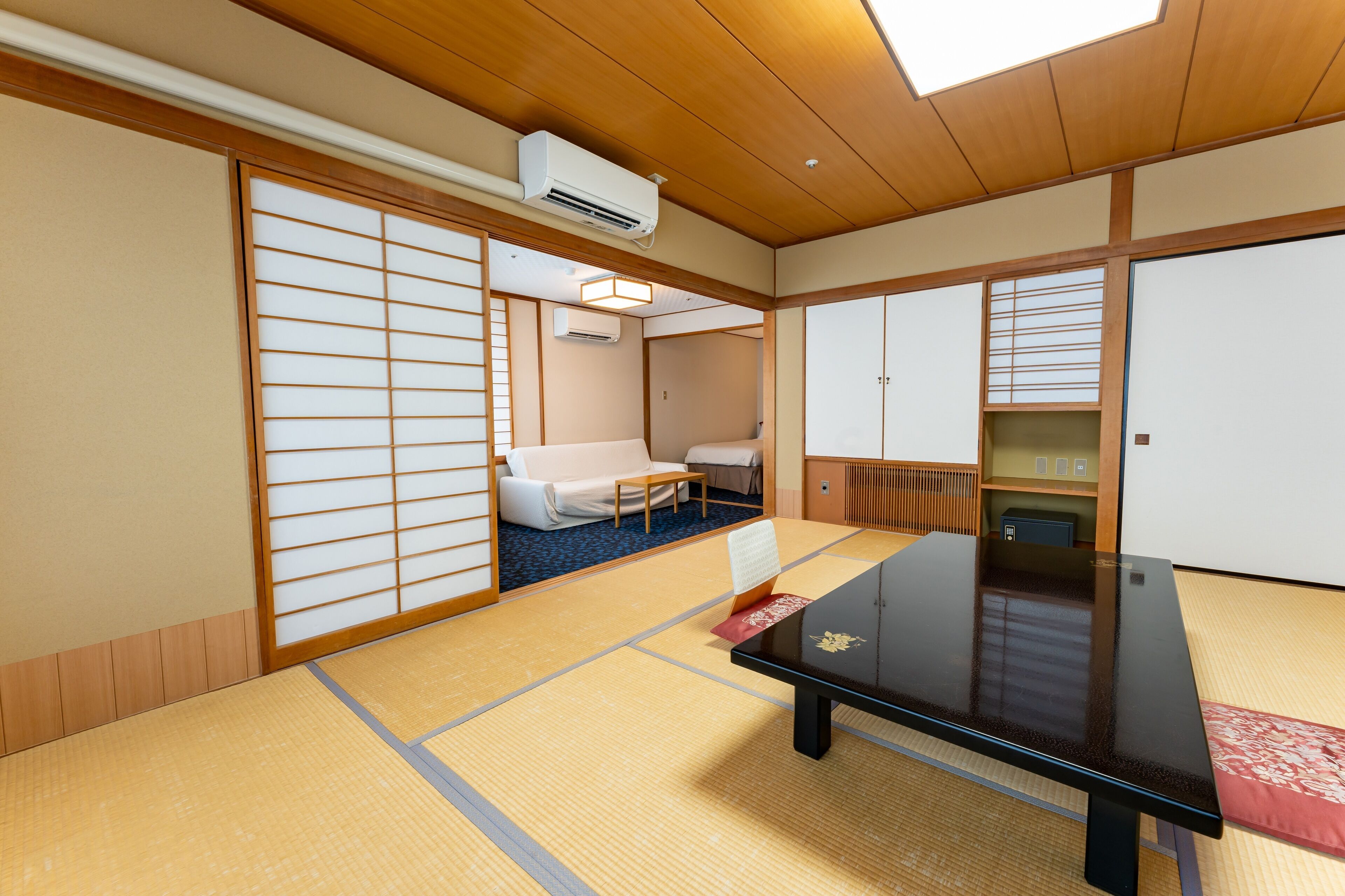 A traditional Japanese room with tatami flooring, a low table, a sofa, and sliding doors.
