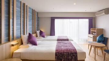 A hotel room with two beds, a desk, a chair, and a window with curtains.