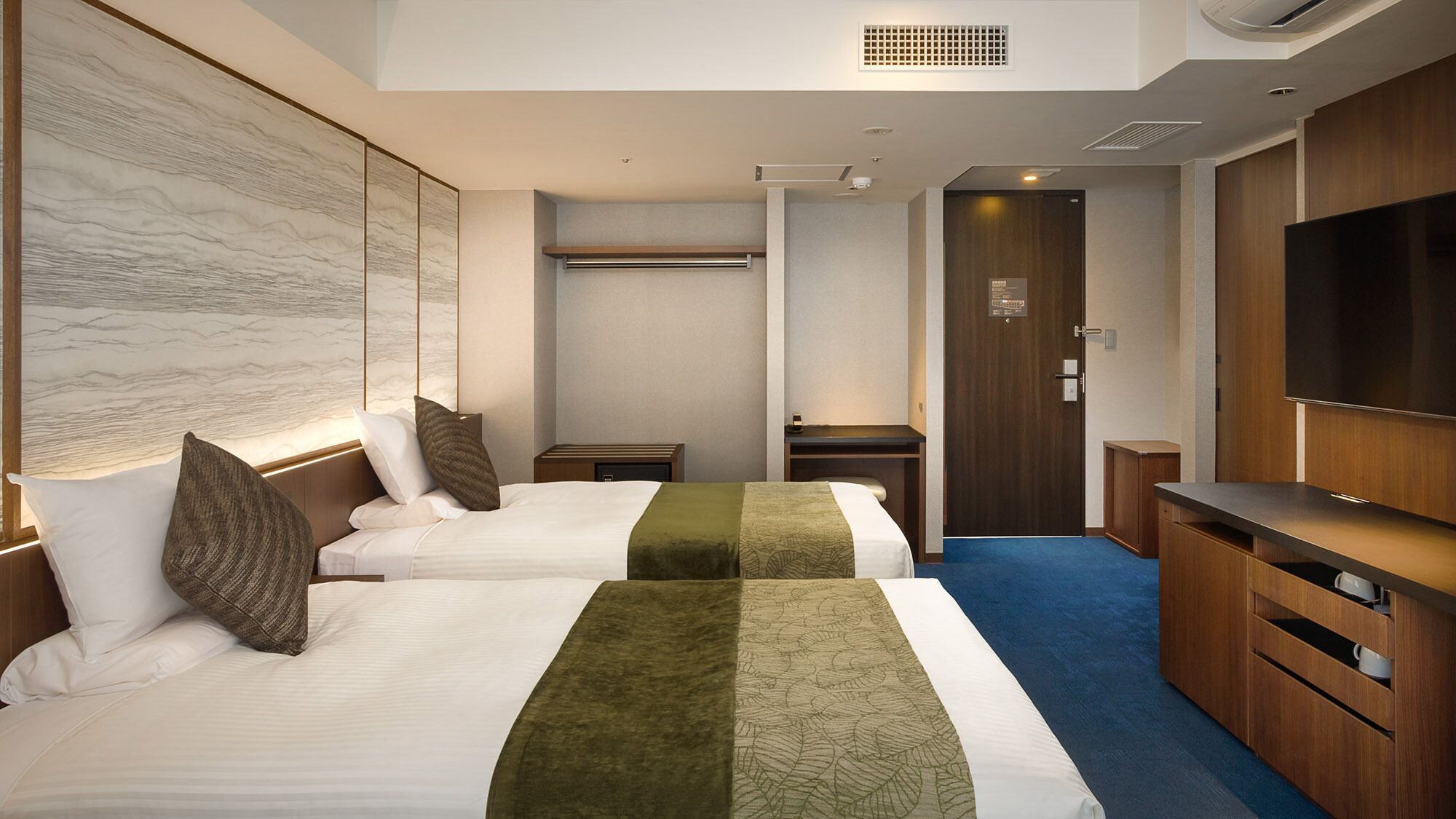 A hotel room with two beds, a TV, a desk, and a wardrobe.