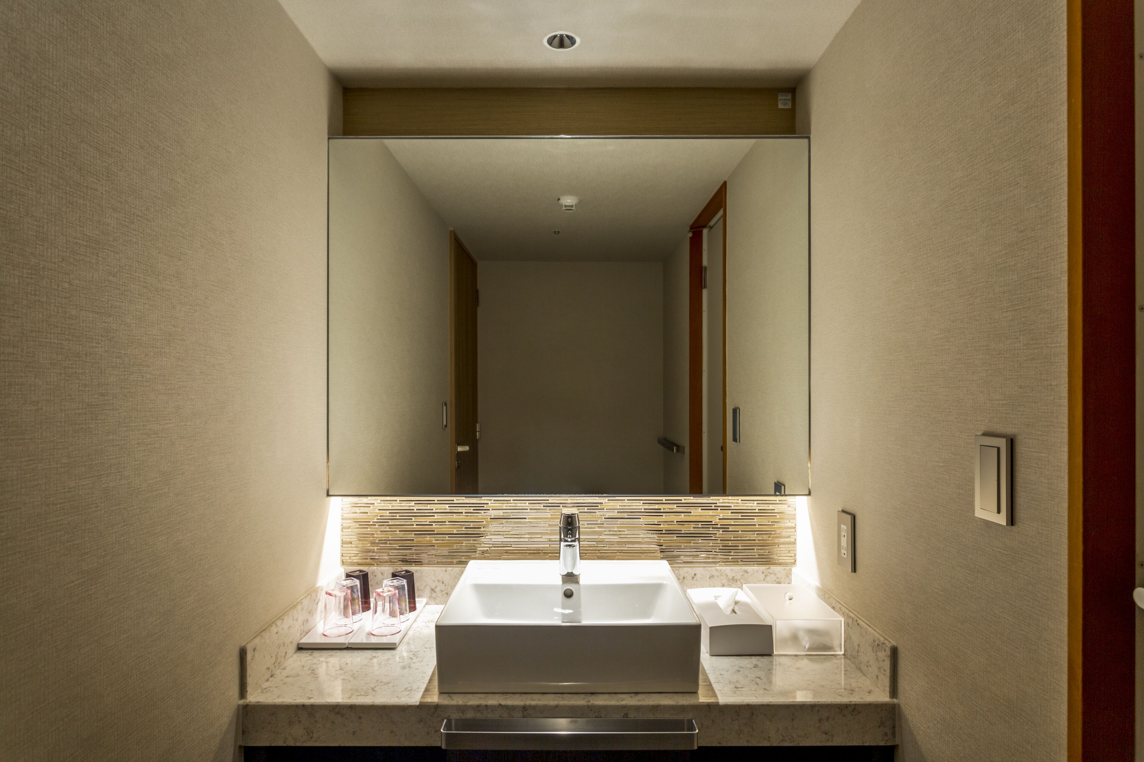 A modern bathroom with a large mirror, a rectangular sink, and a towel rack.