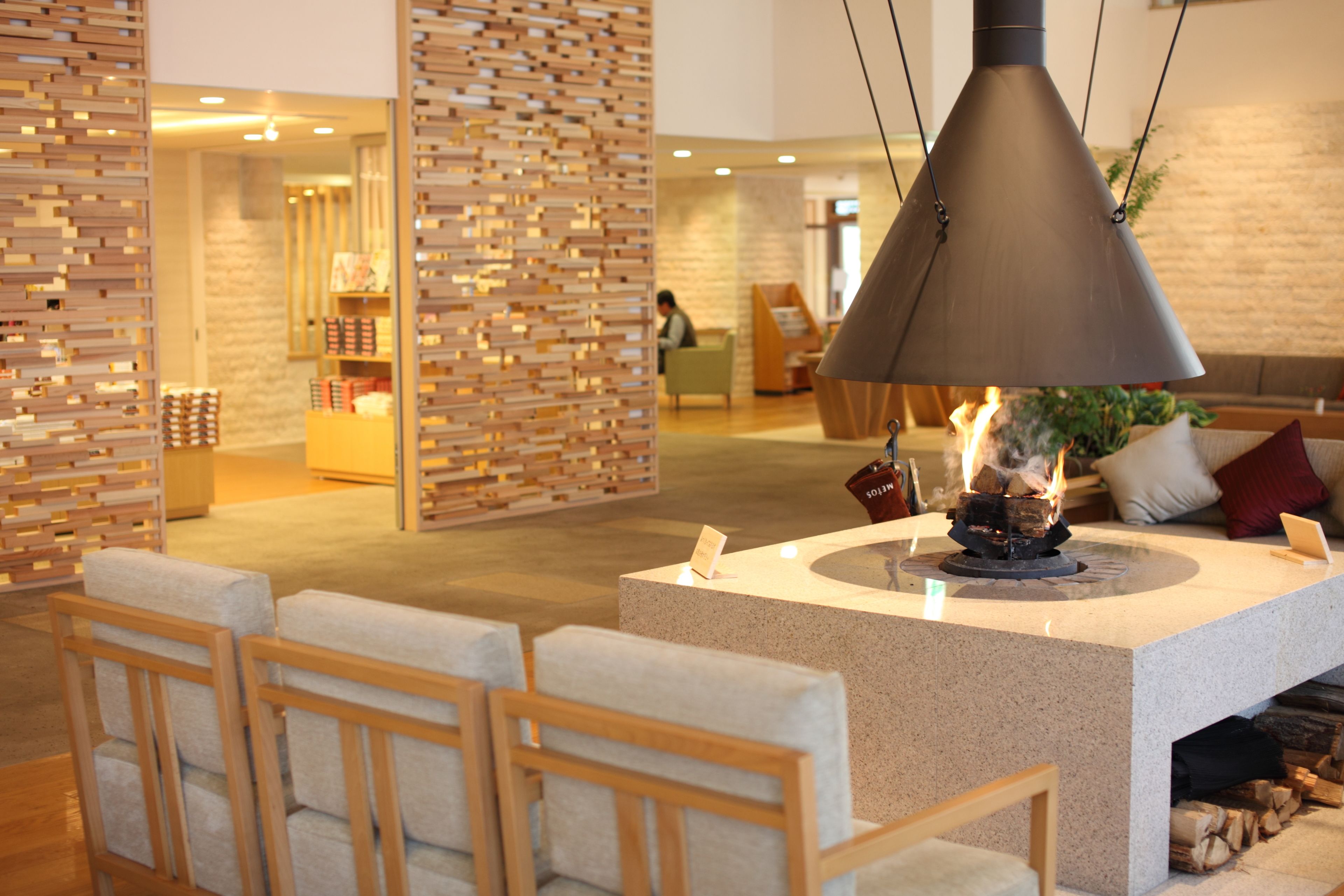A modern interior with a central fire feature, seating area, and a wooden partition.