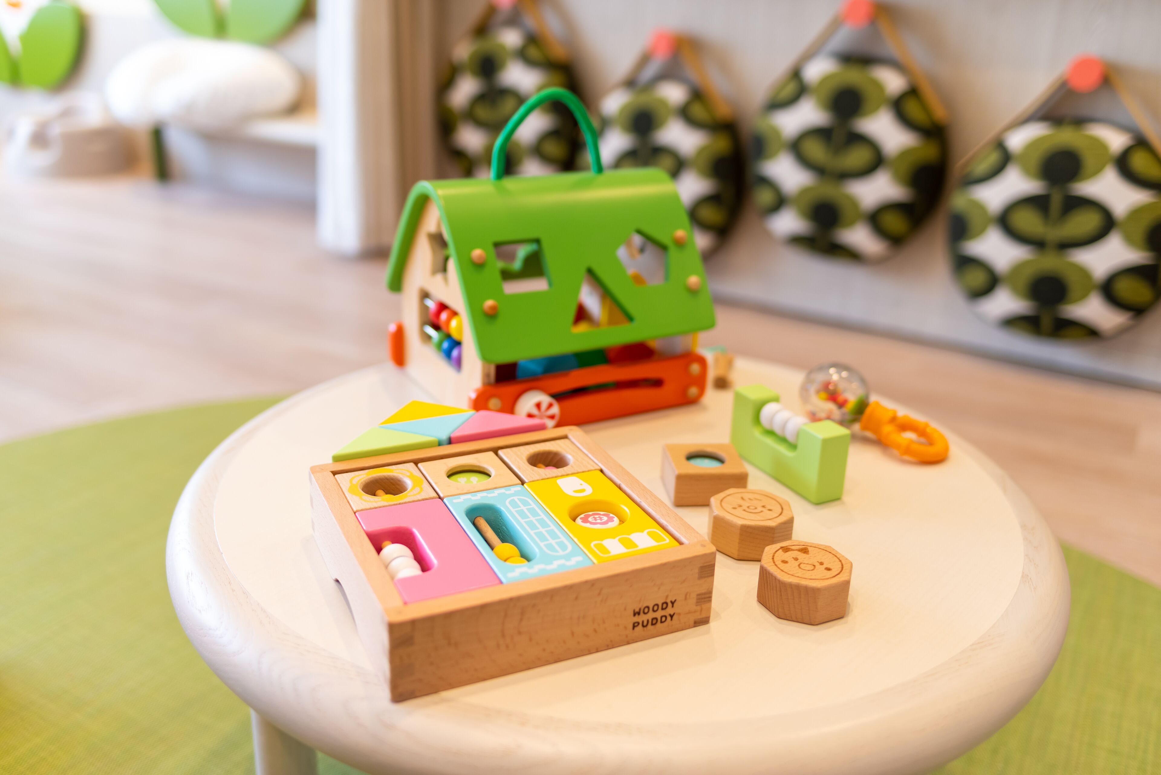 Une maison en bois, servant de jouet, avec un toit vert, posée sur une table blanche.