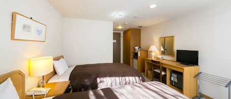 A hotel room with two beds, a desk with a lamp, a television, and a mirror.