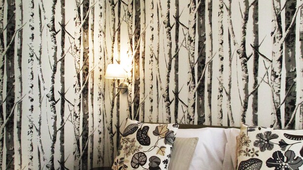 A hotel room with a bed, two pillows, a wall with a vertical pattern, and a wall-mounted lamp. - 15 Quindici by Serendipity Rooms (Milan)