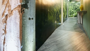 A hallway with a concrete pillar, a wall with a leaf pattern, and a wooden floor. - 15 Quindici by Serendipity Rooms (Milan)