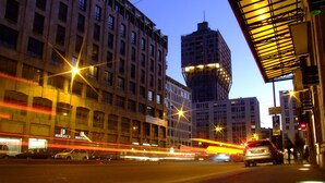 A city street at dusk with modern buildings, including a tall structure with a unique design. - 15 Quindici by Serendipity Rooms (Milan)