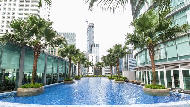 A swimming pool with a tiled edge, surrounded by palm trees and modern buildings in the background. - Saba Suites at Vortex KLCC Bukit Bintang (Kuala Lumpur)
