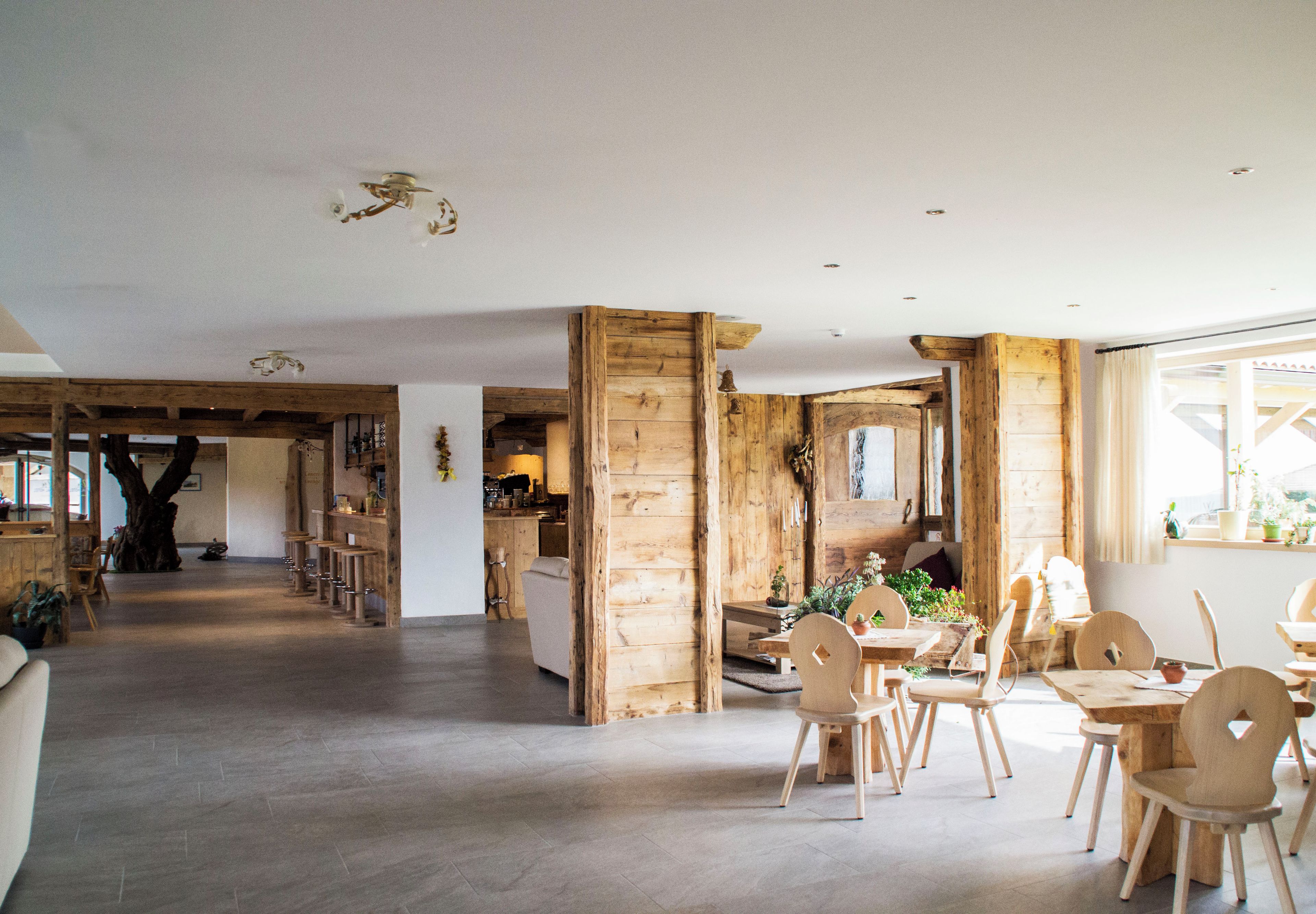 A spacious room with a wooden dining area, a kitchen in the background, and a large window.