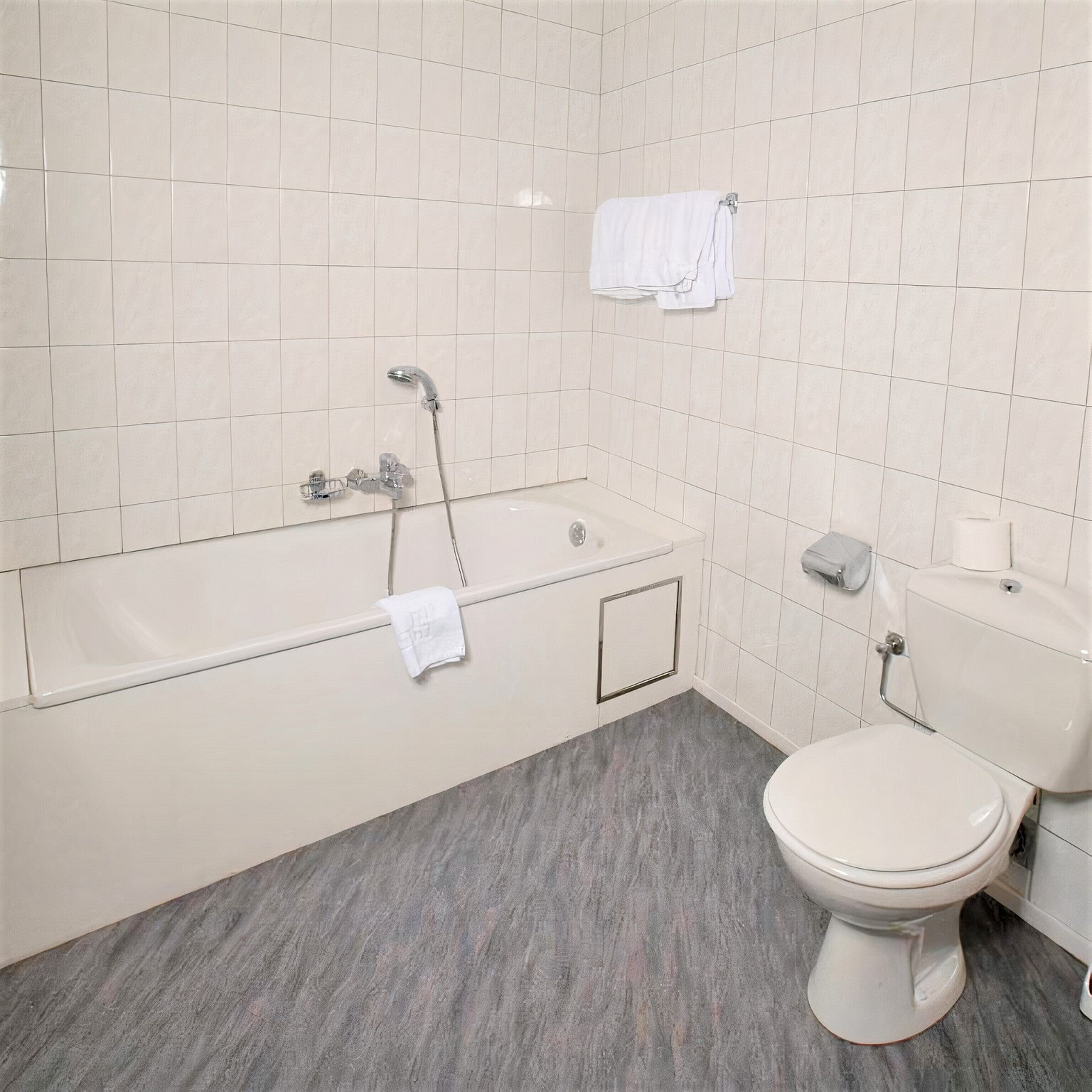A bathroom with a bathtub, toilet, and a towel rack.