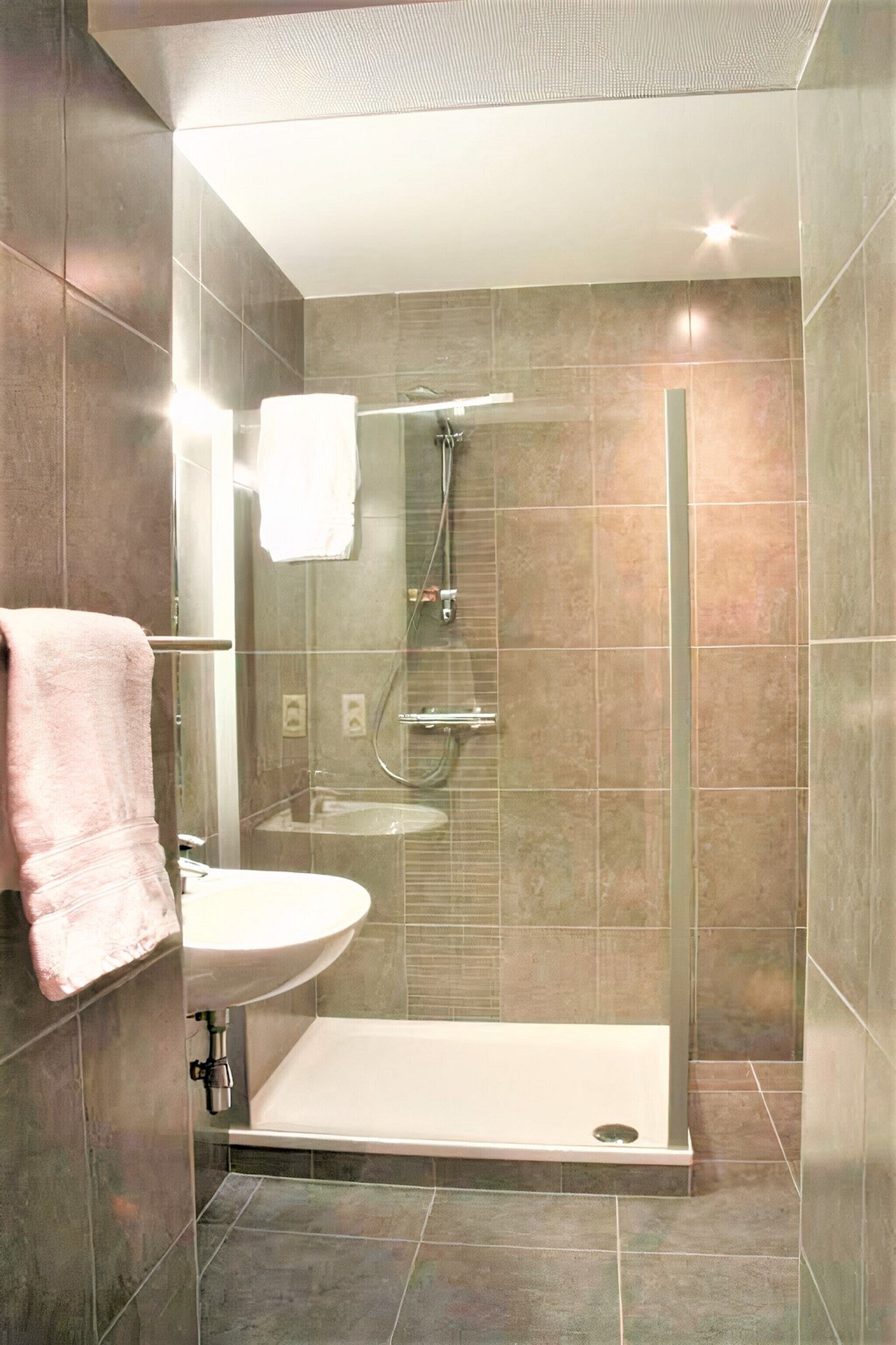 A modern bathroom with a glass-enclosed shower, a sink, and a bathtub.