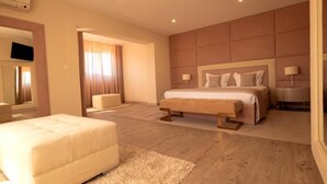 Un dormitorio moderno con una cama grande, un sofá, una mesita y un espejo.