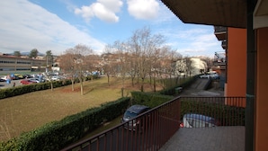 Ein Balkon mit Blick auf einen Parkplatz, Bäume und Gebäude im Hintergrund.