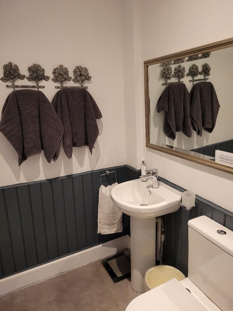 A bathroom with a white sink, a mirror, and towels hanging on a rack.