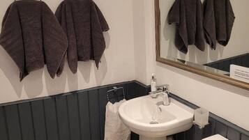 A bathroom with a white sink, a mirror, and towels hanging on a rack.